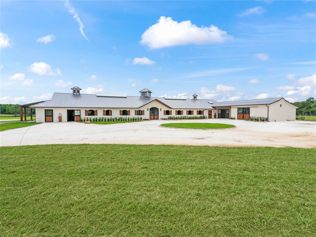 A long, single-story equestrian barn with a metal roof and multiple stall doors — 2380 NW 72ND COURT, OCALA, FL