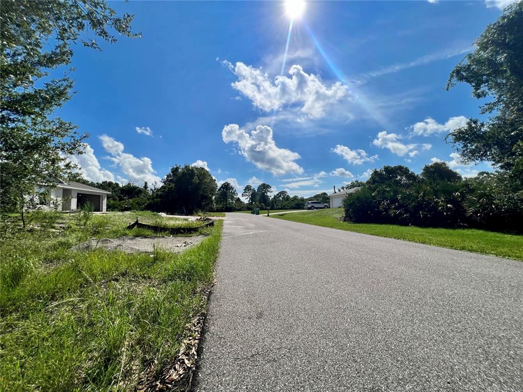 A paved residential street leads toward a vacant lot with a house under construction nearby — 5542 EYERLY TERRACE, PORT CHARLOTTE, FL