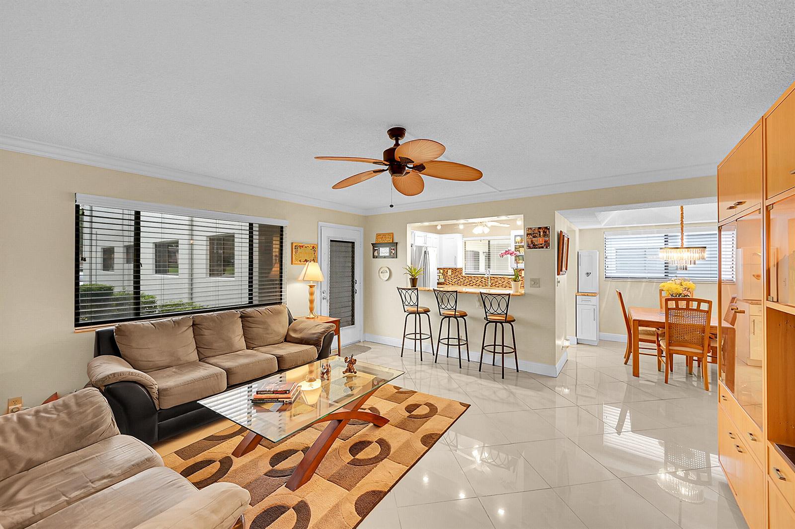 A living room with tile floors, a ceiling fan, and an adjacent kitchen and dining area — 15108 Ashland Drive # 198, Delray Beach FL 33484, DELRAY BEACH, FL