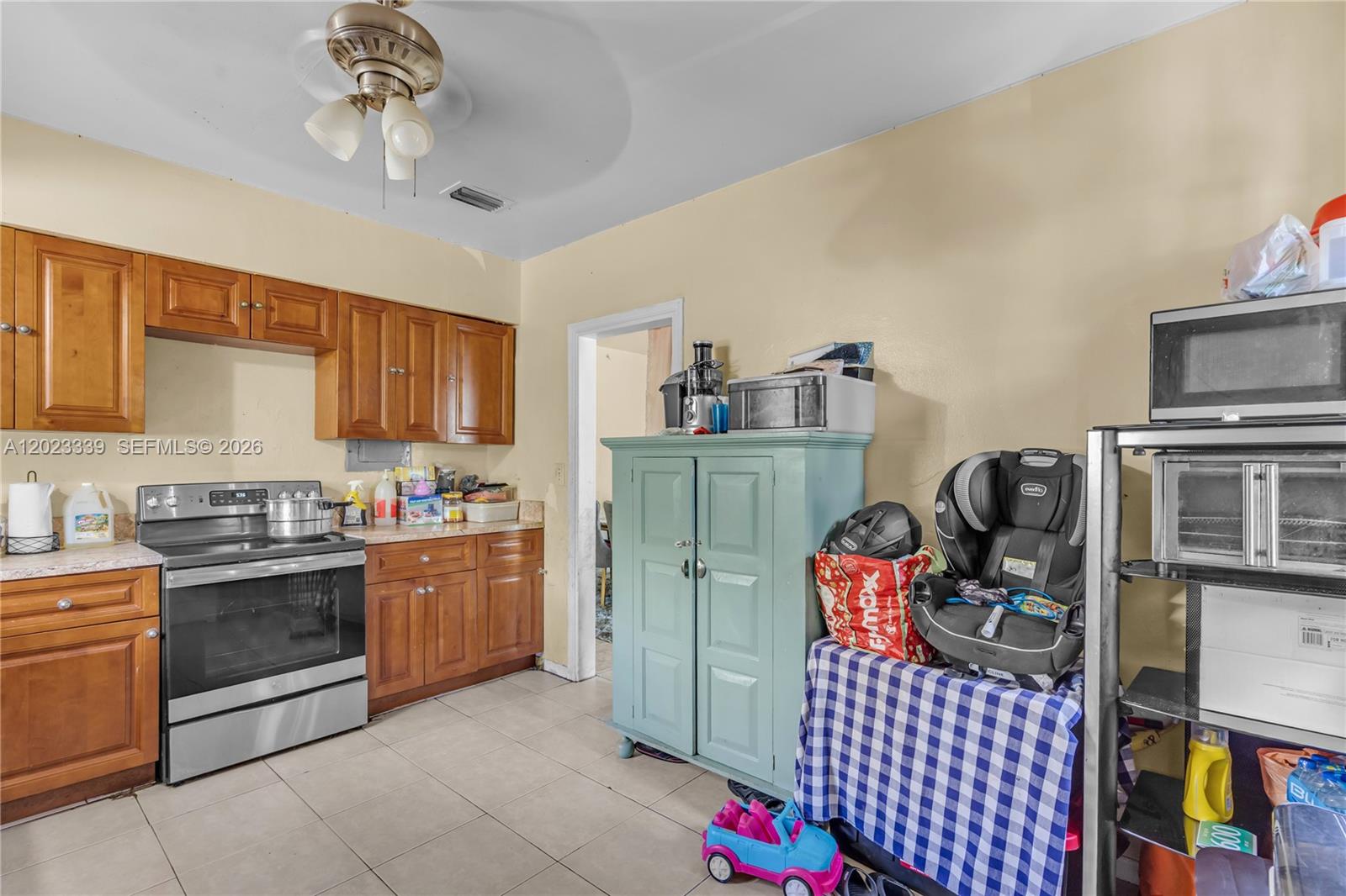 A kitchen features wooden cabinets, a stainless steel stove, and a light blue storage cabinet — 94 NW 69th St, Miami FL 33150, MIAMI, FL