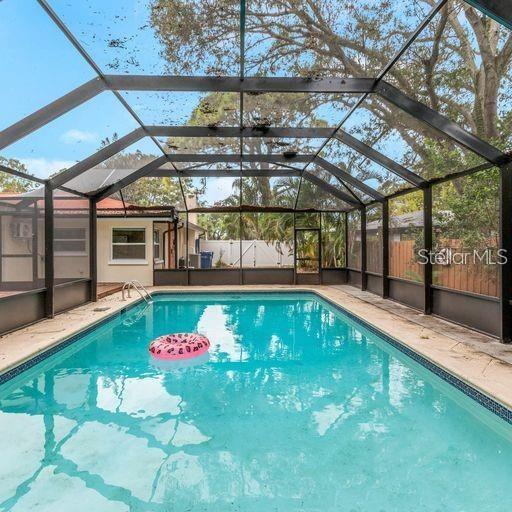 A swimming pool is enclosed by a screened-in lanai attached to a residential house — 2608 OAKWOOD DRIVE, LARGO, FL