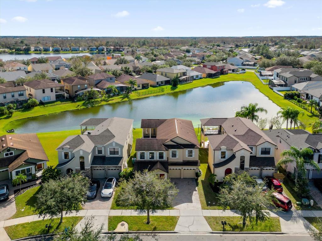 An aerial view shows three suburban houses with driveways facing a pond in a neighborhood — 9657 MOSS ROSE WAY, ORLANDO, FL