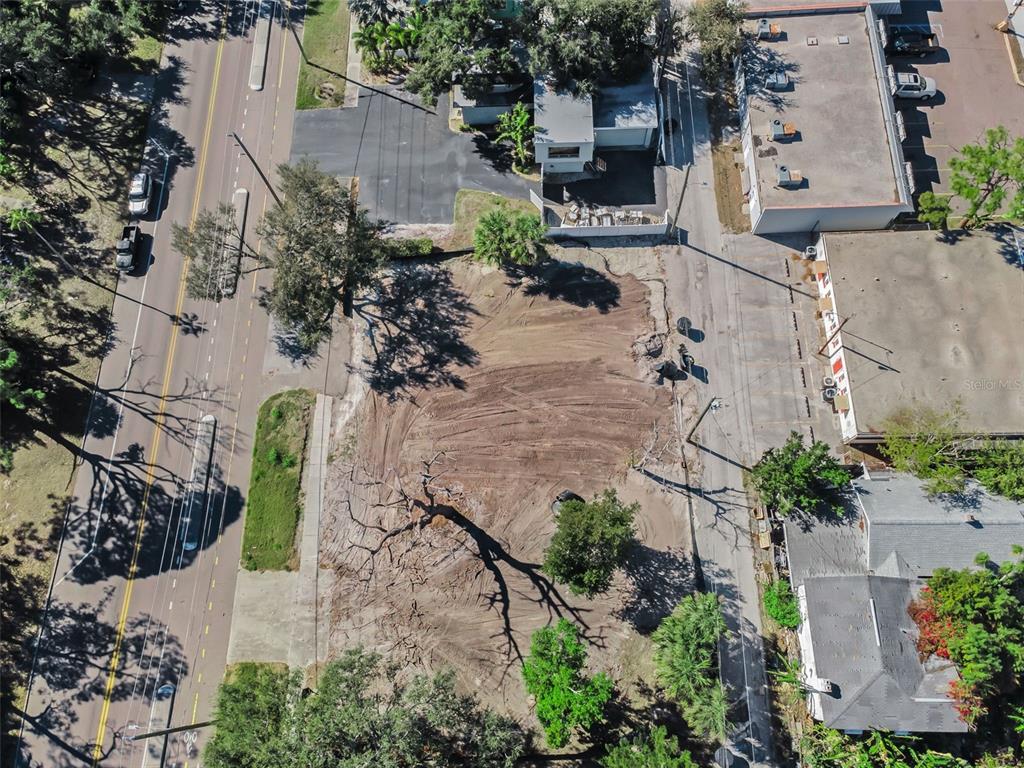 An aerial view shows a cleared, vacant lot situated between a road and commercial buildings — 7301 1ST AVENUE S, ST PETERSBURG, FL