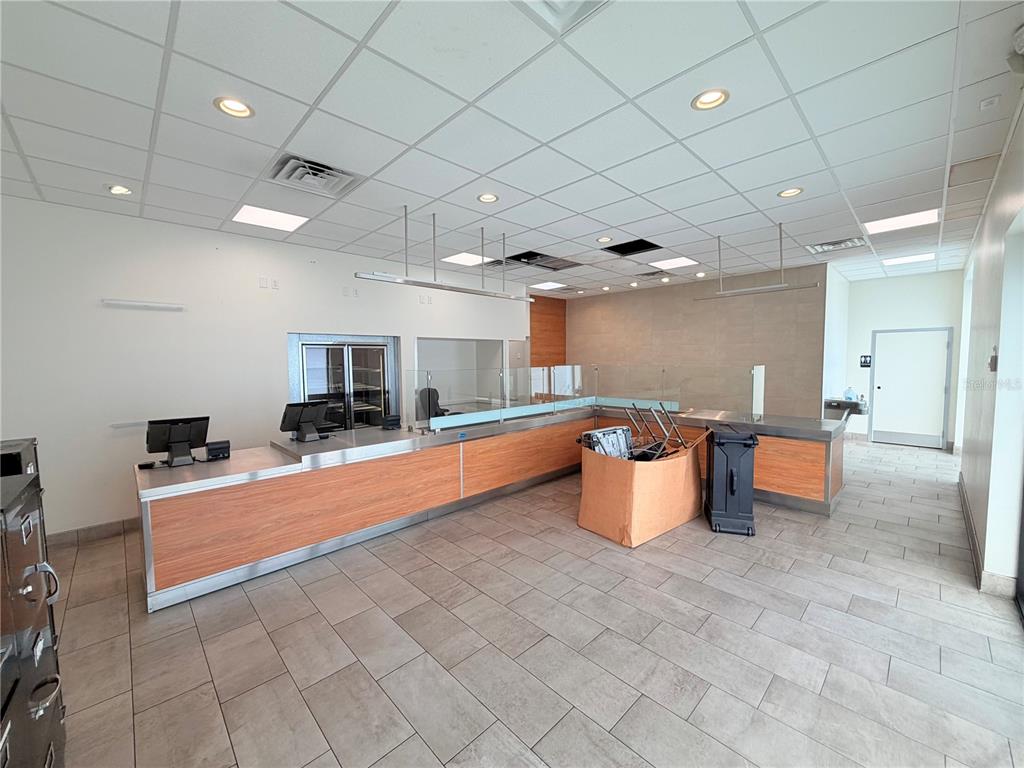 A commercial interior features a long service counter with wood-look panels and tile flooring — 6011 SE ABSHIER BOULEVARD, BELLEVIEW, FL