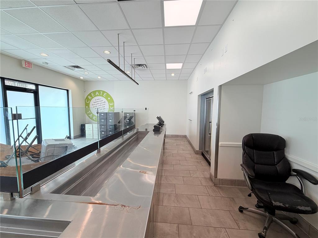 A commercial space features a long stainless steel counter, tile flooring, and a glass partition — 6011 SE ABSHIER BOULEVARD, BELLEVIEW, FL