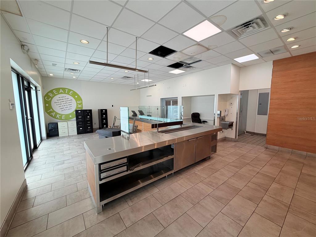 A commercial kitchen space features stainless steel counters, tile flooring, and a drop ceiling — 6011 SE ABSHIER BOULEVARD, BELLEVIEW, FL
