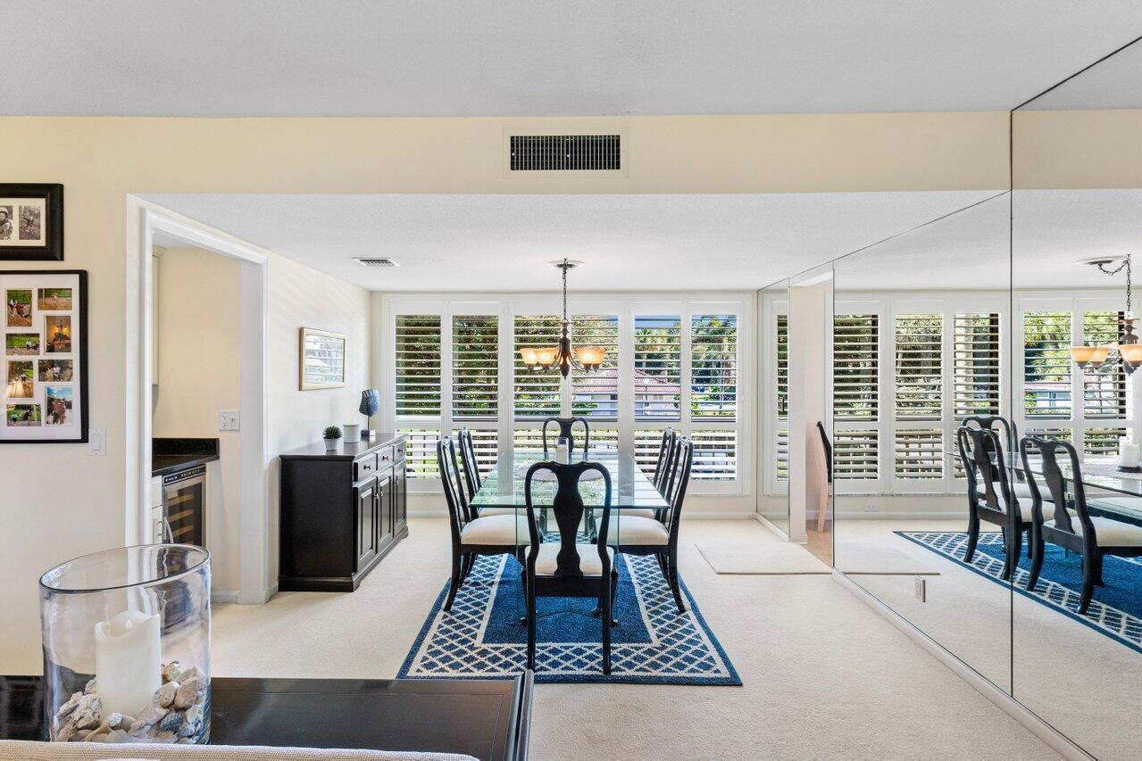 A dining room features a glass table, blue patterned rug, and mirrored wall panels — 4643 Kittiwake Court, Boynton Beach FL 33436, BOYNTON BEACH, FL
