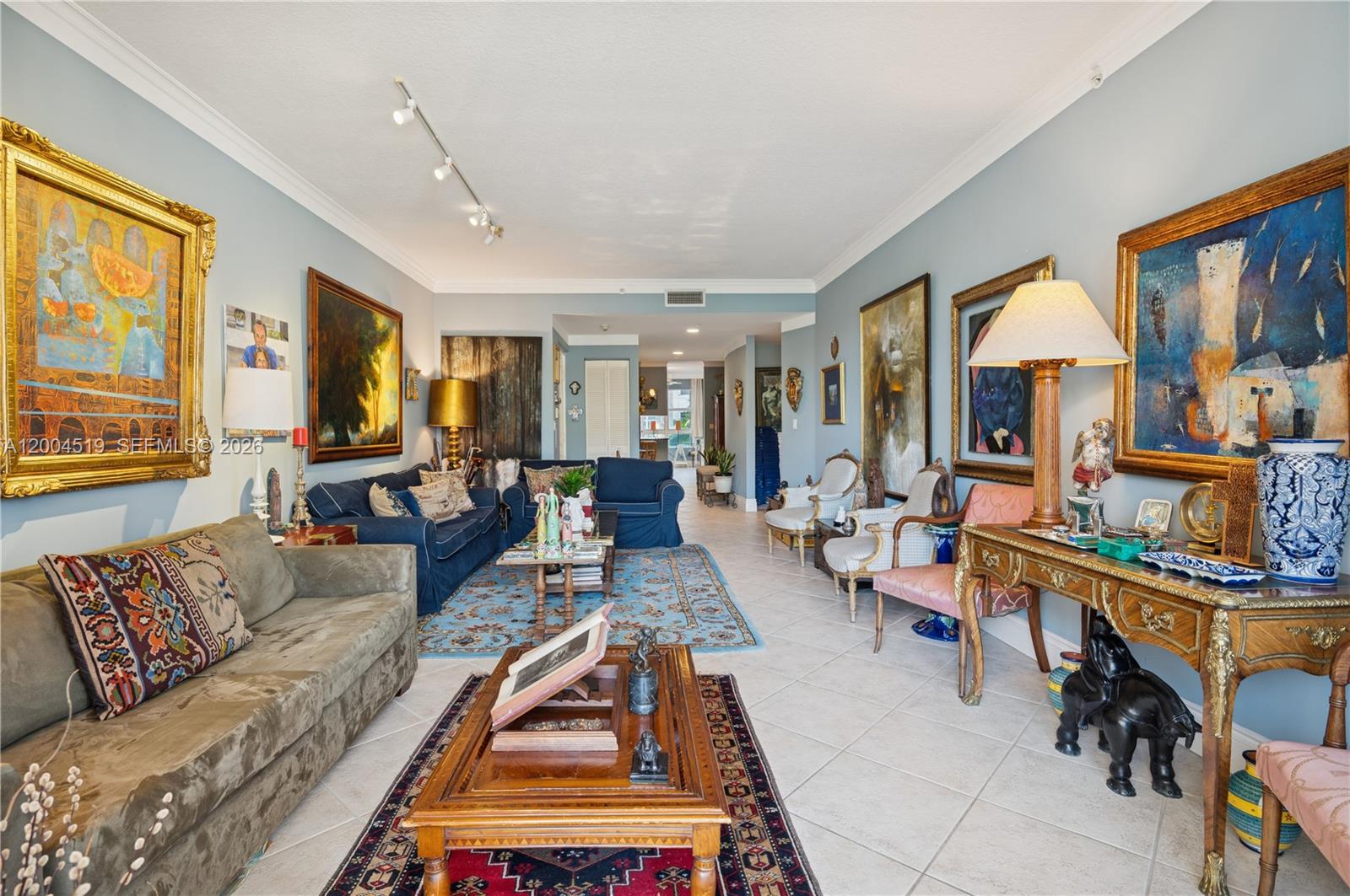 A living room features multiple framed paintings, two sofas, a wooden coffee table, and area rugs — 719 Crandon Blvd # 310, Key Biscayne FL 33149, KEY BISCAYNE, FL