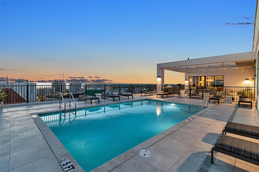A rooftop swimming pool with lounge chairs overlooks a city skyline at sunset — 33 S PALM AVENUE UNIT 701, SARASOTA, FL