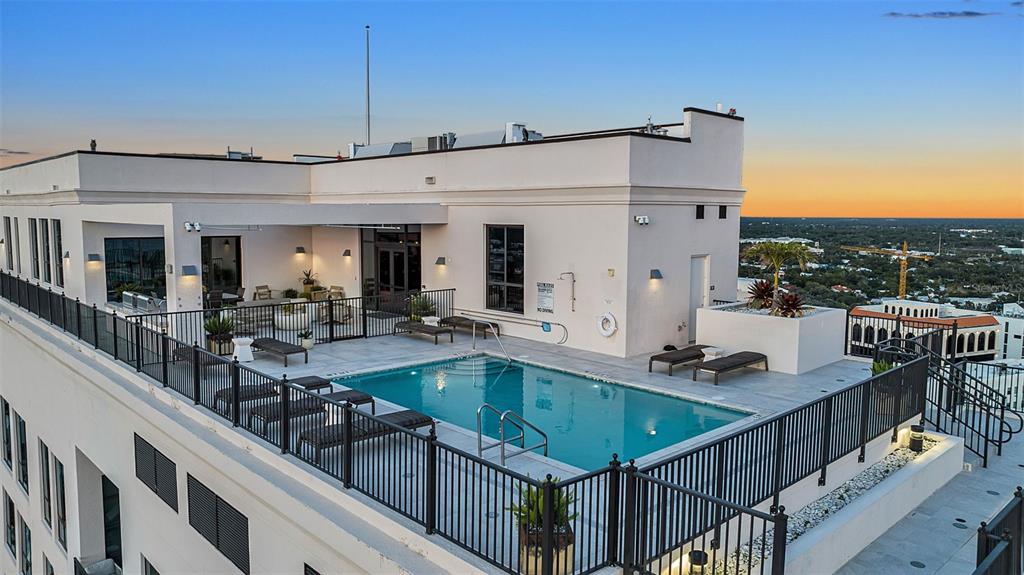 An elevated rooftop terrace features a swimming pool surrounded by lounge chairs and metal railings — 33 S PALM AVENUE UNIT 701, SARASOTA, FL