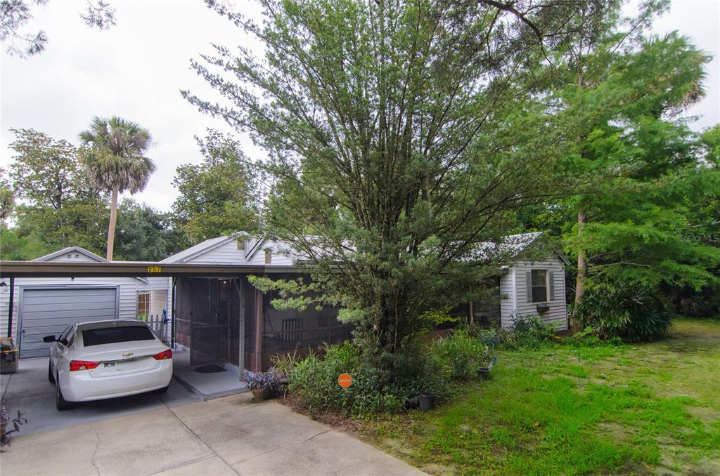 A white house with a carport, a screened-in porch, and a large tree in the yard — 257 DESOTO AVENUE, DE LEON SPRINGS, FL