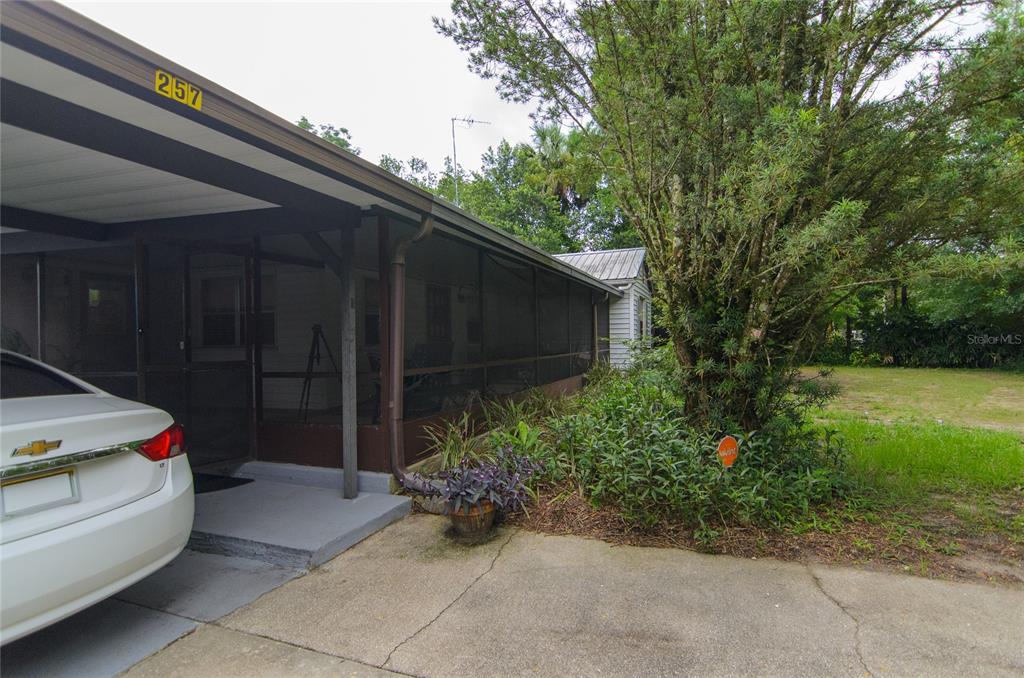 A white car is parked under a carport next to a screened-in porch — 257 DESOTO AVENUE, DE LEON SPRINGS, FL