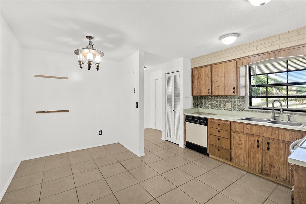 A kitchen and dining area with tile flooring, wood cabinets, and a window above the sink — 977 WHIPORWILL DRIVE, PORT ORANGE, FL