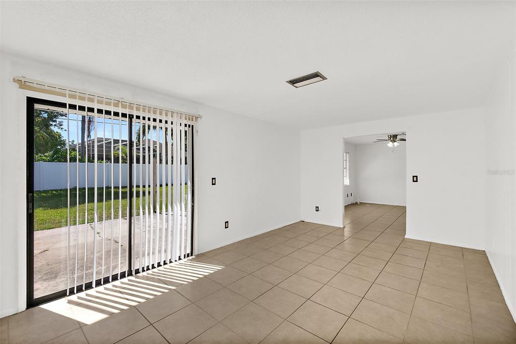 An empty room with beige tile flooring, white walls, and a sliding glass door — 977 WHIPORWILL DRIVE, PORT ORANGE, FL