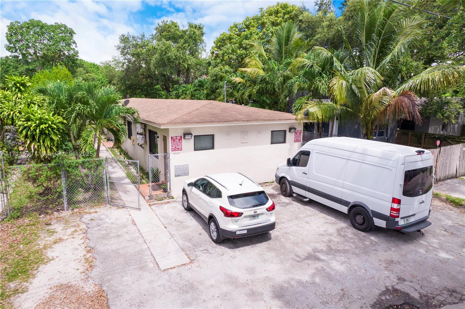 An exterior view of a single-story building with a gravel parking area and two vehicles — 5520 NE 1st Ct, Miami FL 33137, MIAMI, FL