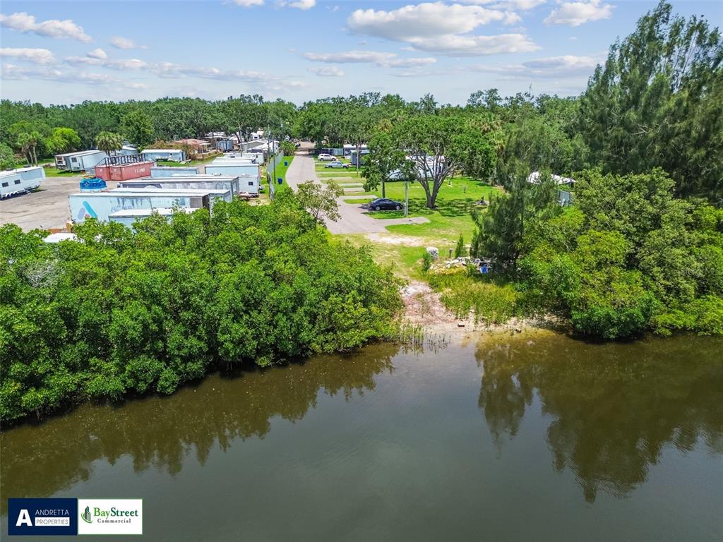 An aerial view shows a waterfront property with mobile homes, storage containers, and trees — 11224 RESTWOOD DRIVE, GIBSONTON, FL
