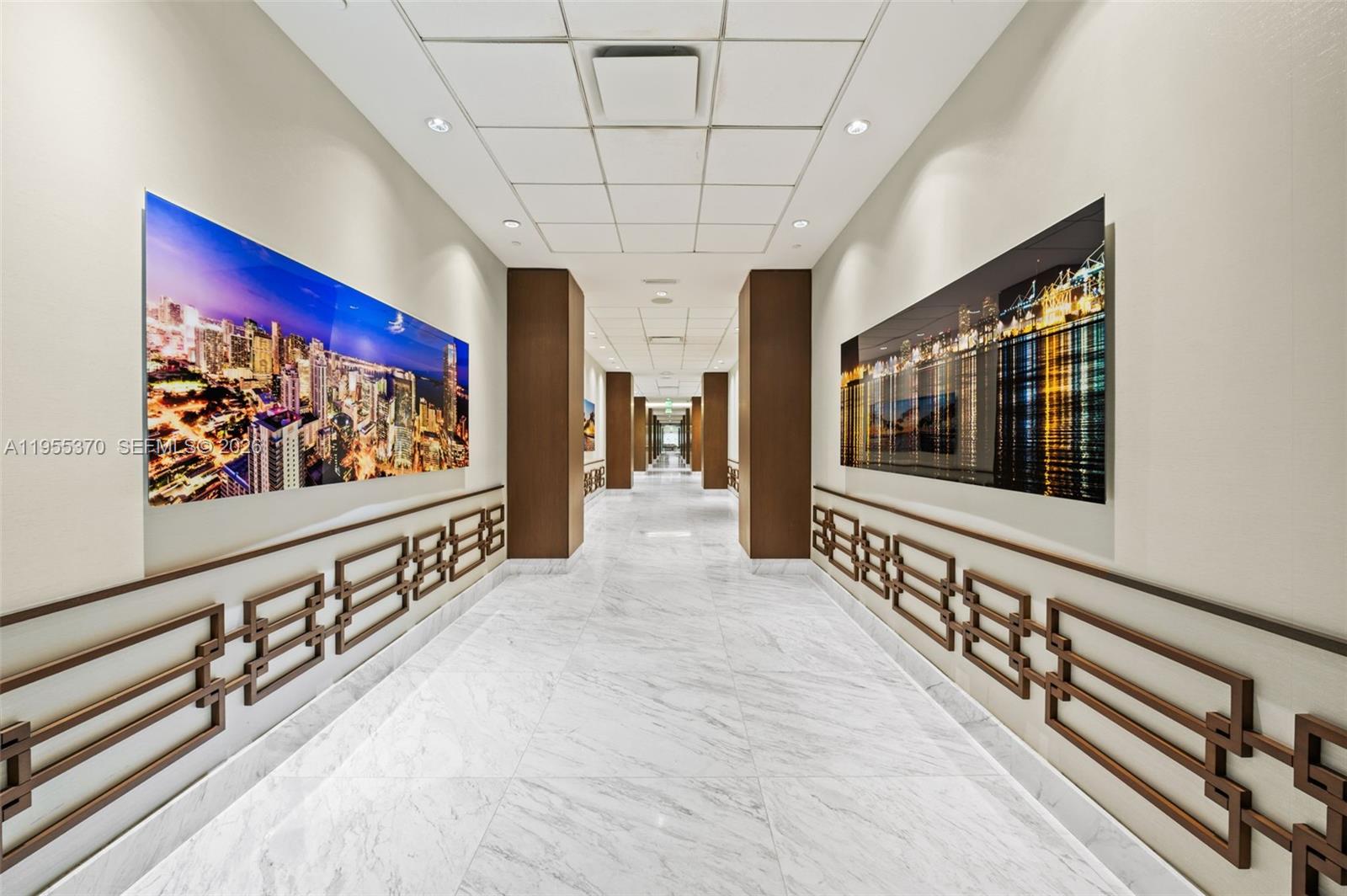 A long hallway features marble floors, decorative wall trim, and large city-themed wall art — 10155 Collins Ave # 909, Bal Harbour FL 33154, BAL HARBOUR, FL