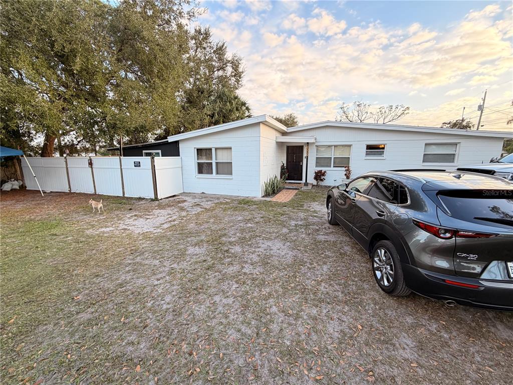 A single-story white house with a gravel driveway and a parked SUV in the foreground — 7326 SHEFFIELD ROAD, TAMPA, FL
