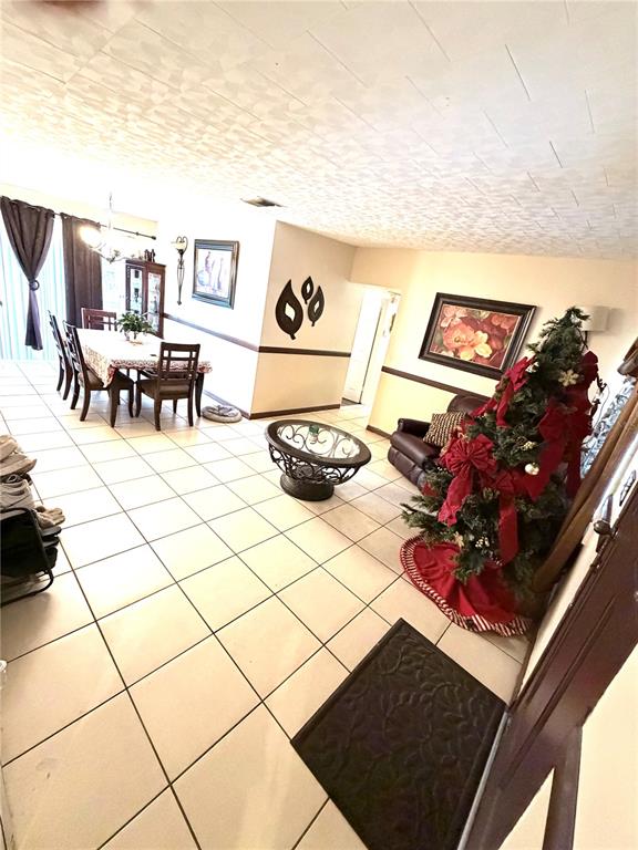A tiled dining and living area features a Christmas tree and a glass-topped coffee table — 7326 SHEFFIELD ROAD, TAMPA, FL