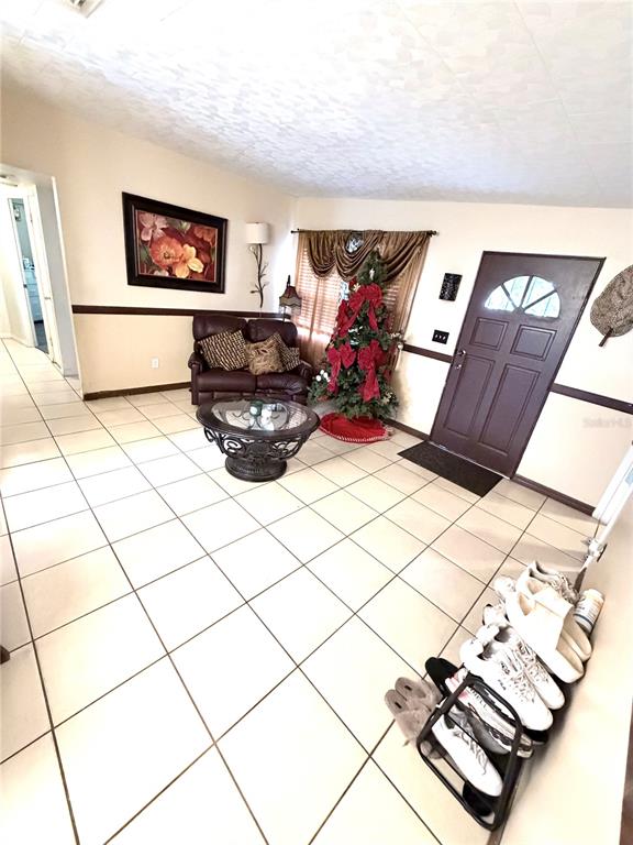 A living room features tiled floors, a brown loveseat, a coffee table, and a Christmas tree — 7326 SHEFFIELD ROAD, TAMPA, FL