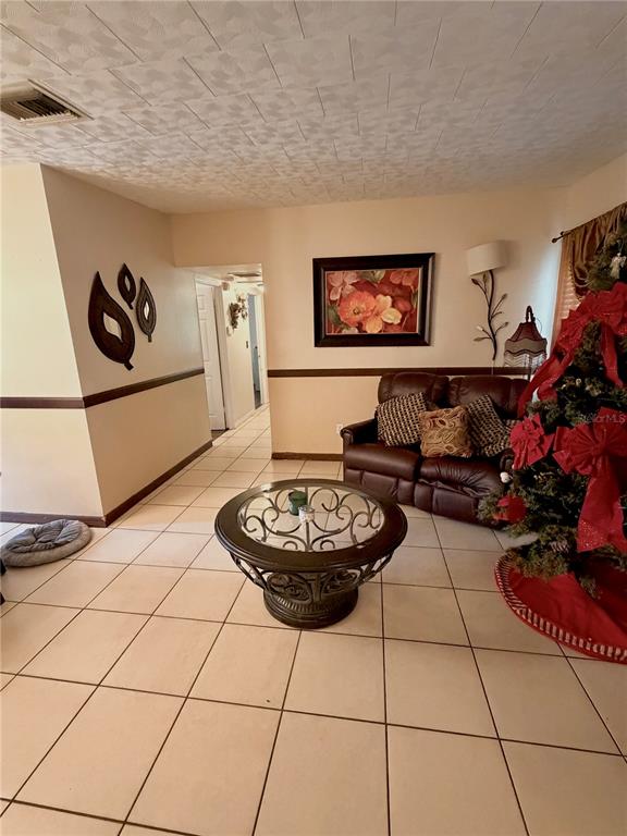 A living room features tile flooring, a brown leather loveseat, and a round glass coffee table — 7326 SHEFFIELD ROAD, TAMPA, FL