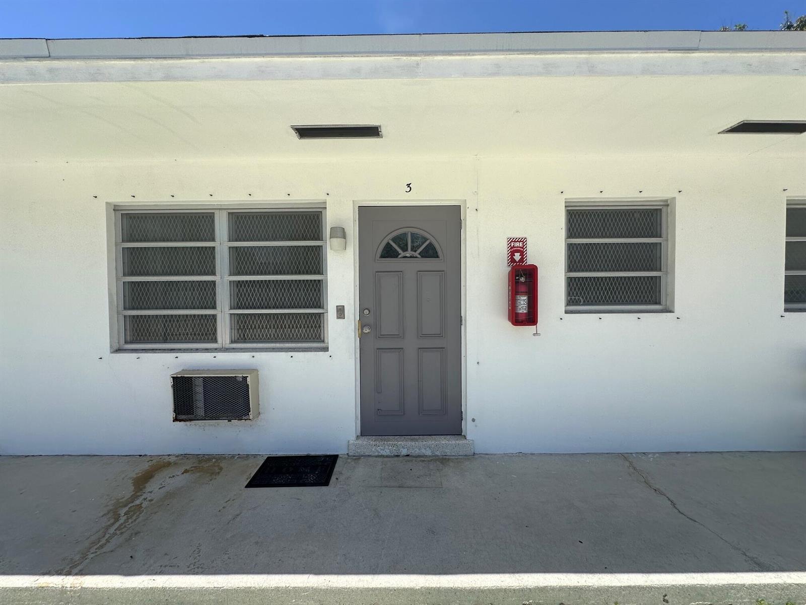 A white exterior wall features a grey door labeled number 3, windows, and a fire extinguisher — 932 S B Street # 3, FL 33460, FL