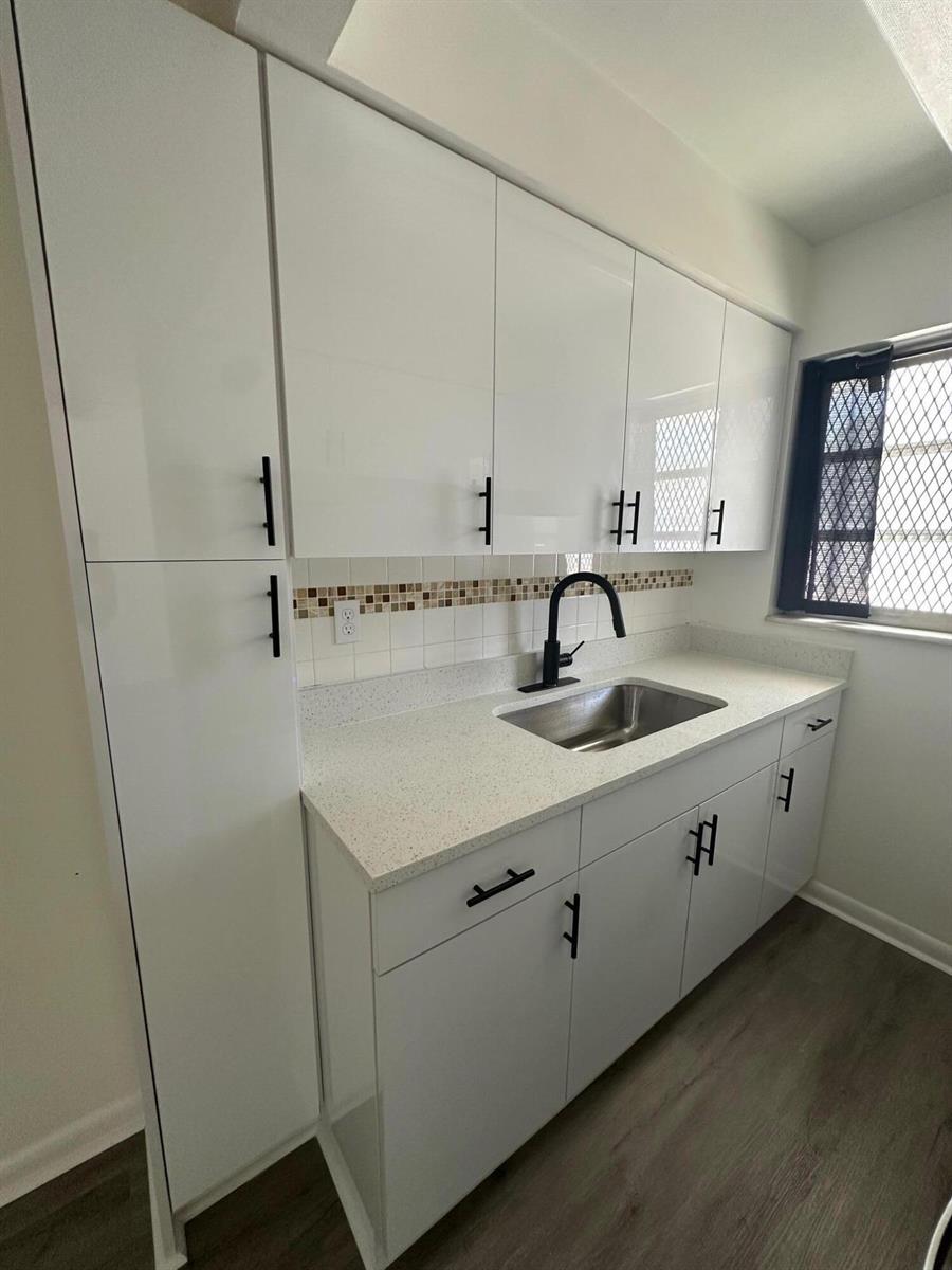 A kitchen features white cabinets, black hardware, a stainless steel sink, and a tiled backsplash — 932 S B Street # 3, FL 33460, FL