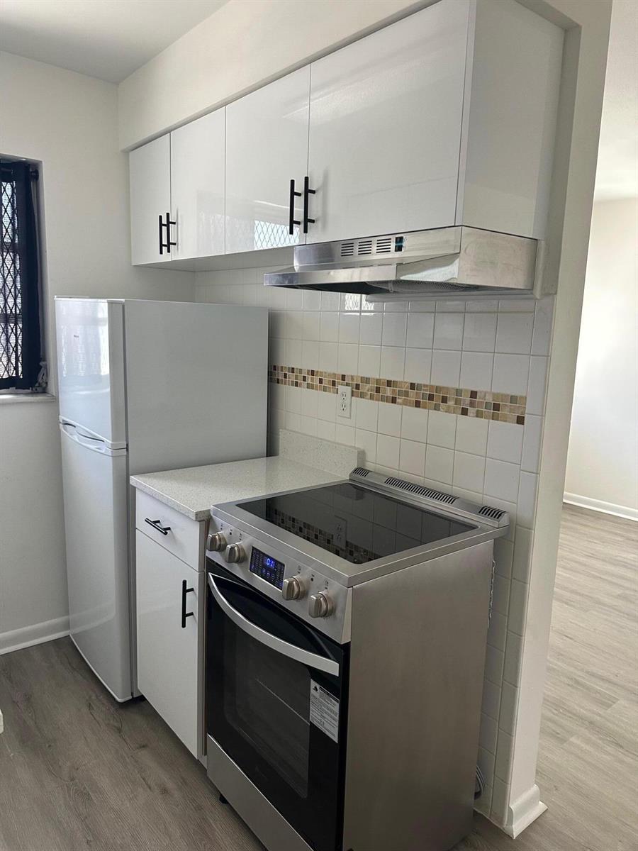 A kitchen features white cabinets, stainless steel appliances, and a tiled backsplash — 932 S B Street # 3, FL 33460, FL