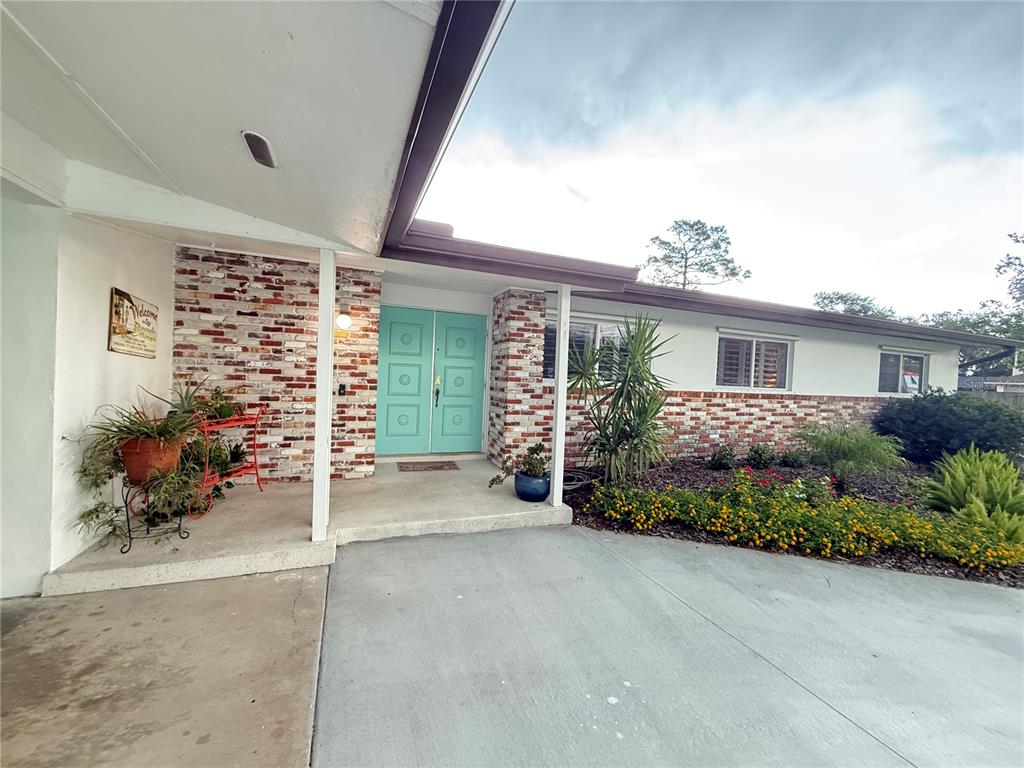 A single-story house features a brick facade, teal double front doors, and a concrete driveway — 801 FAIRWAY DRIVE, NEW SMYRNA BEACH, FL