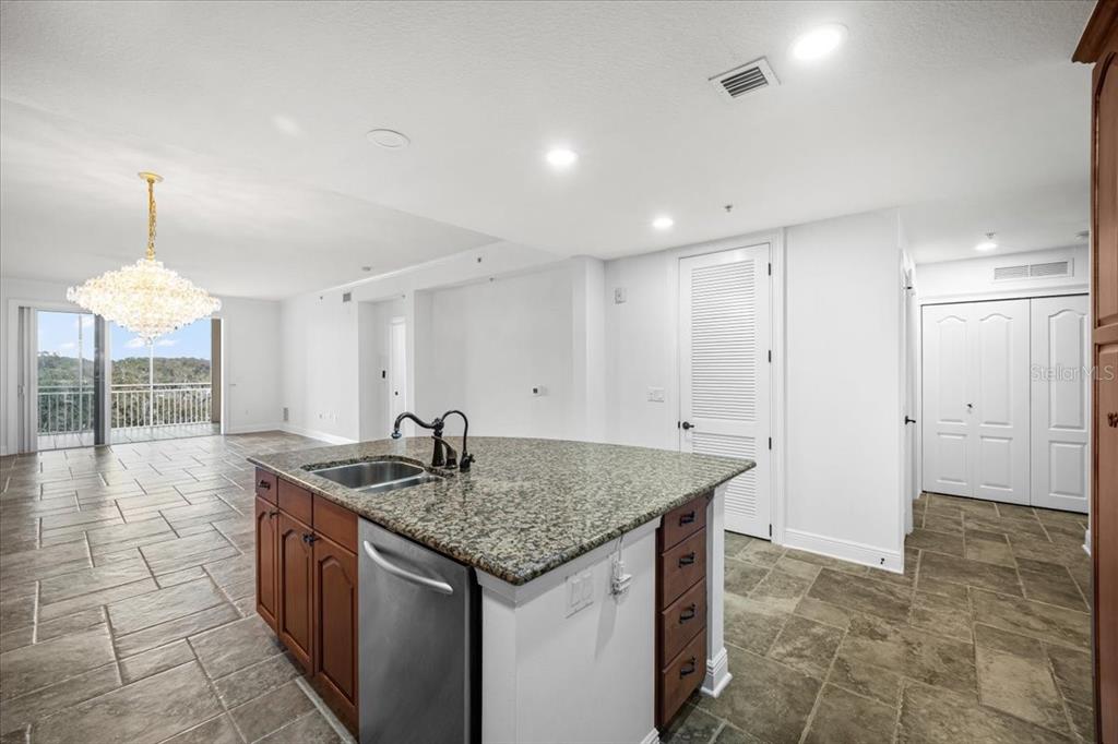 A kitchen island with granite countertops and a stainless steel dishwasher sits on tiled flooring — 146 PALM COAST RESORT BOULEVARD UNIT 509, PALM COAST, FL