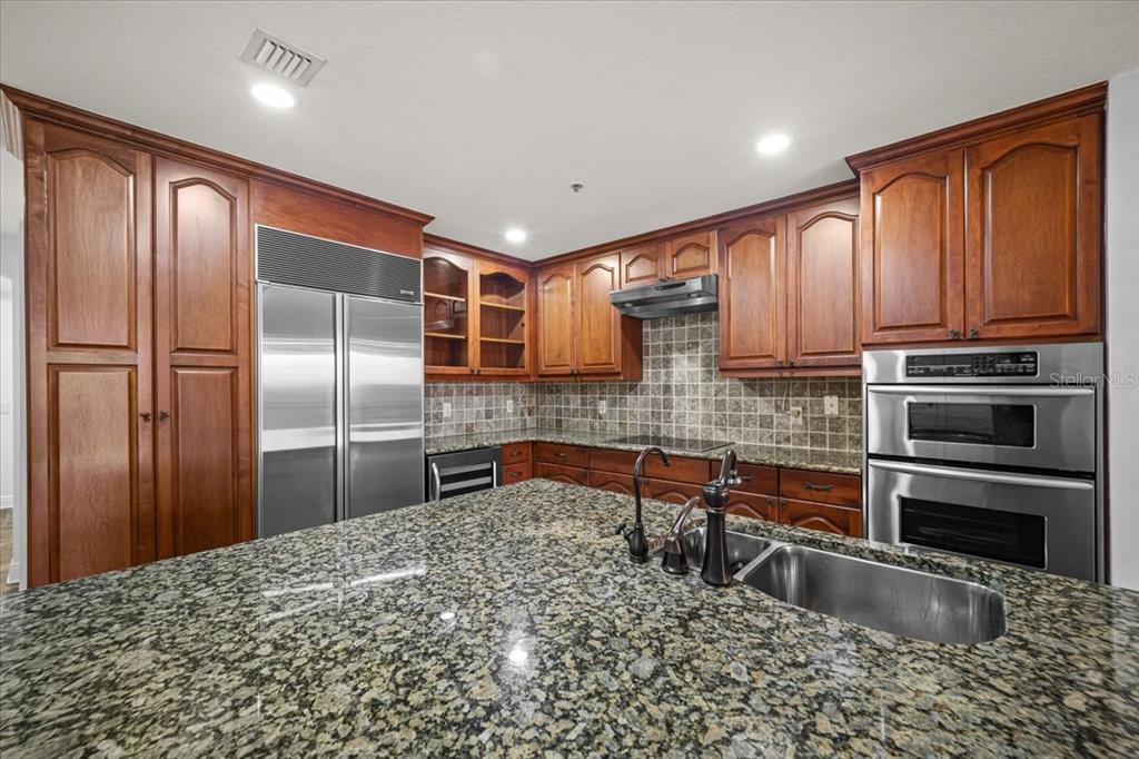 A kitchen features wood cabinets, granite countertops, a large island, and stainless steel appliances — 146 PALM COAST RESORT BOULEVARD UNIT 509, PALM COAST, FL