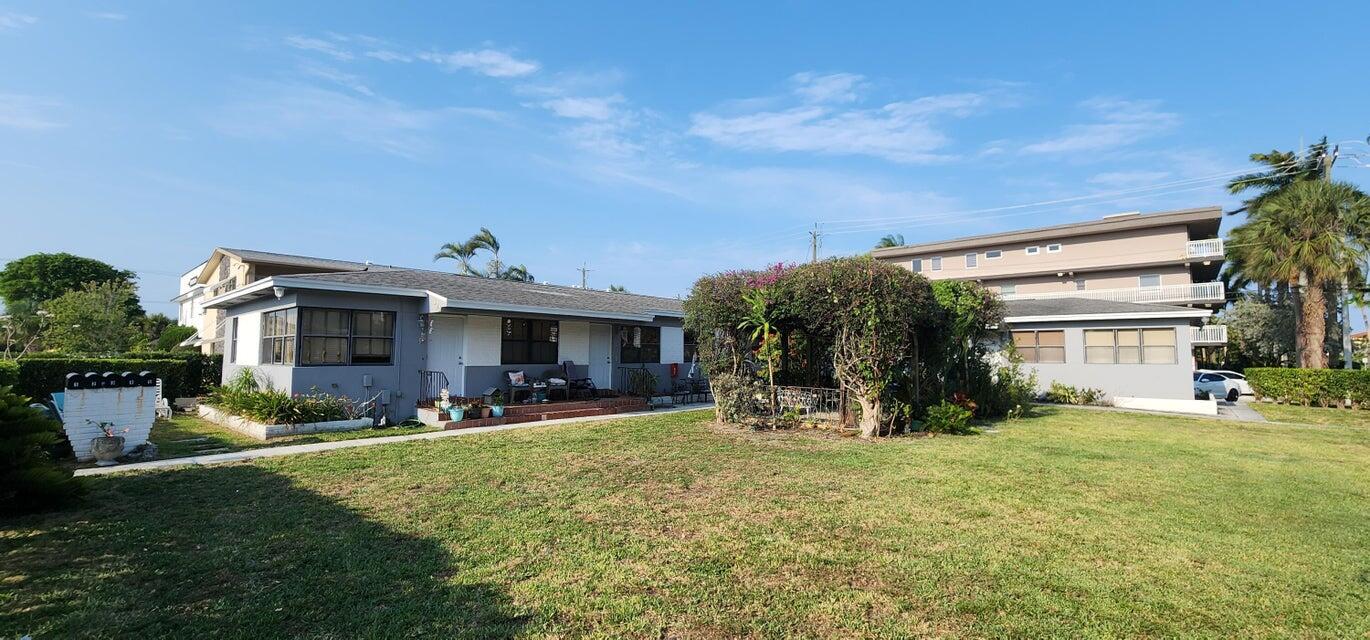 A single-story gray house with a lawn and a gazebo next to a larger building — 130 S Lakeside 1 Drive, FL 33460, FL