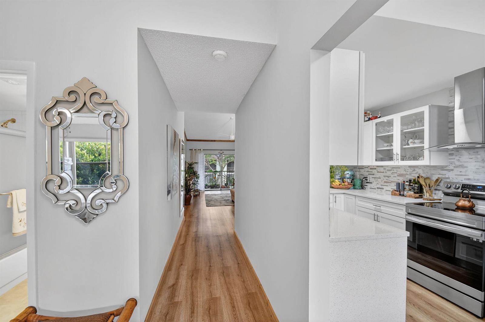 A hallway with wood-look flooring leads from a kitchen to a living area with balcony — 7855 Willow Spring Drive # 725, Lake Worth FL 33467, LAKE WORTH, FL