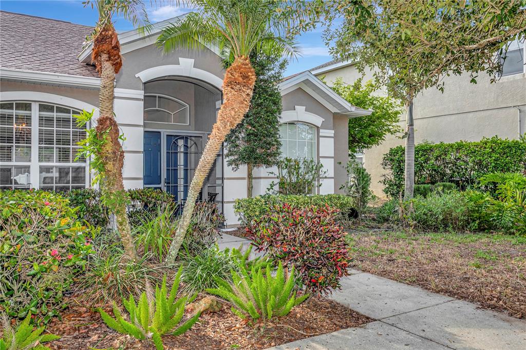 A gray house with white trim, a arched entryway, and palm trees in the front yard — 4105 30TH LANE E, BRADENTON, FL