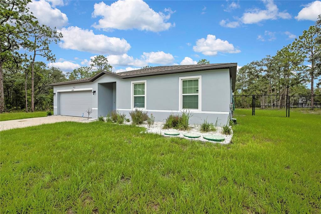 A single-story house with a gray exterior, a garage, and a landscaped front yard — 16125 MAGPIE ROAD, WEEKI WACHEE, FL