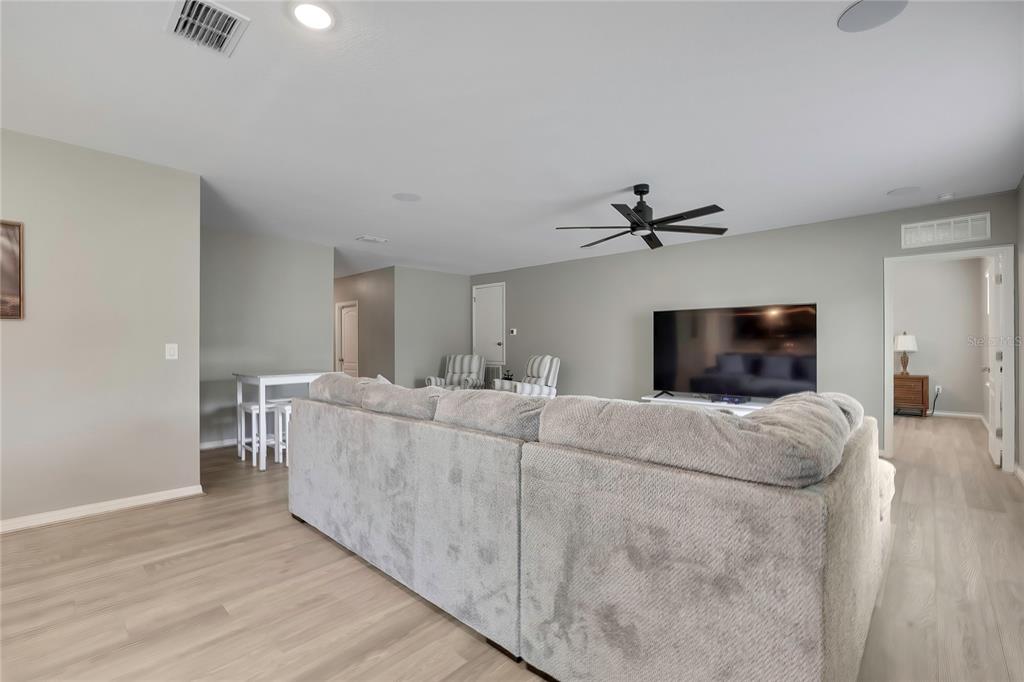 A living room features light wood-look flooring, a gray sectional sofa, and a ceiling fan — 16125 MAGPIE ROAD, WEEKI WACHEE, FL