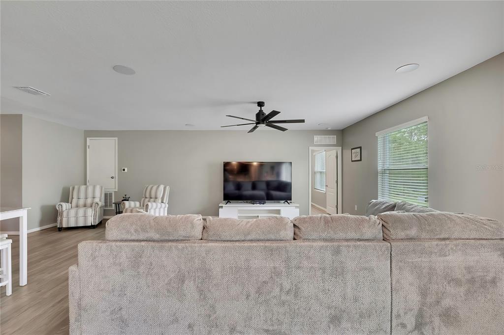 A living room features a large sectional sofa, two striped armchairs, and a television console — 16125 MAGPIE ROAD, WEEKI WACHEE, FL