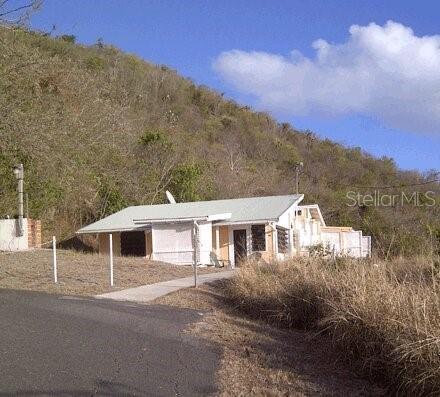 A single-story house with a light-colored roof sits at the base of a grassy hill — End of Road CAM PLAYA TAMARINDO, CULEBRA, PR