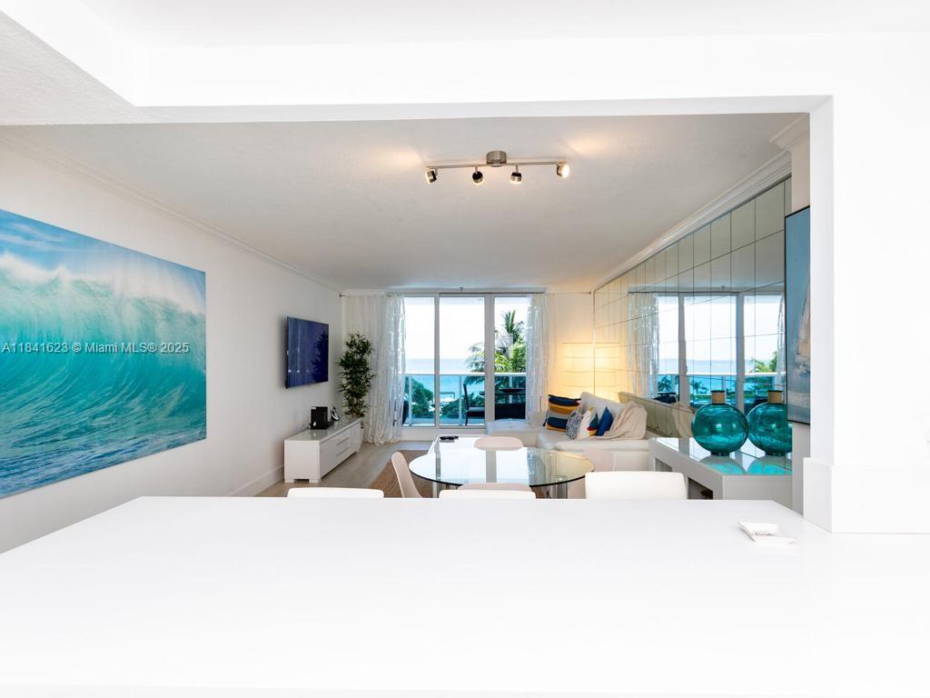A bright living room features a large wave mural, mirrored wall, and balcony with ocean views — 2301 Collins Ave # 625, Miami Beach FL 33139, MIAMI BEACH, FL