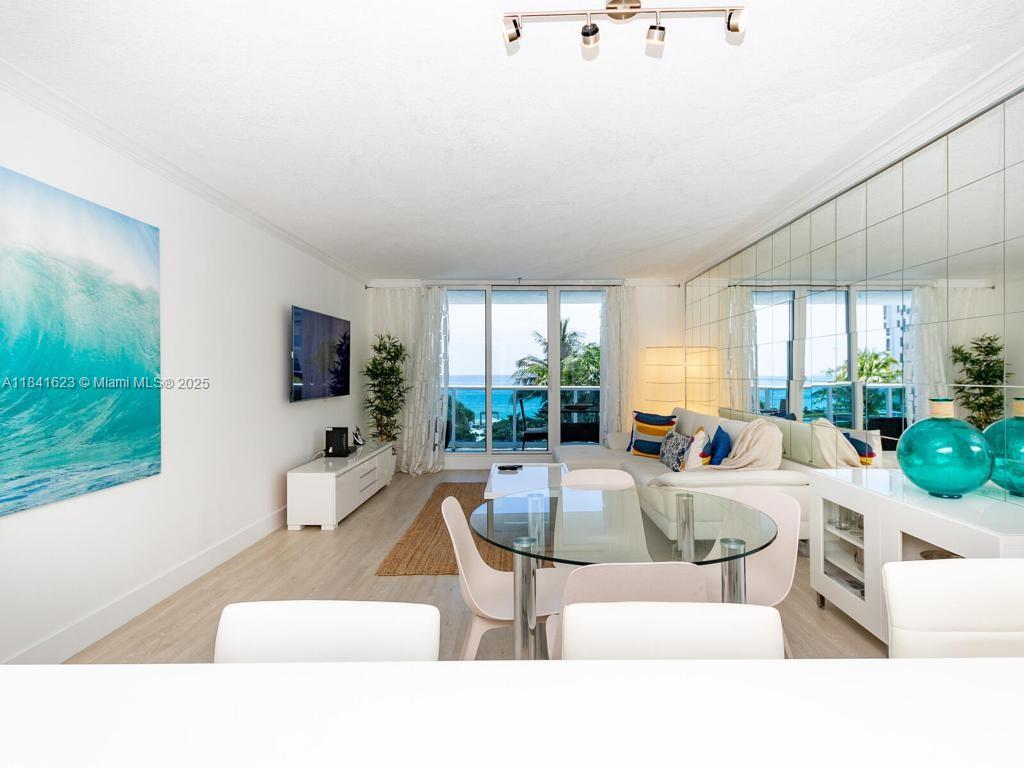 A living and dining area features a glass table, mirrored wall, and ocean view balcony — 2301 Collins Ave # 625, Miami Beach FL 33139, MIAMI BEACH, FL