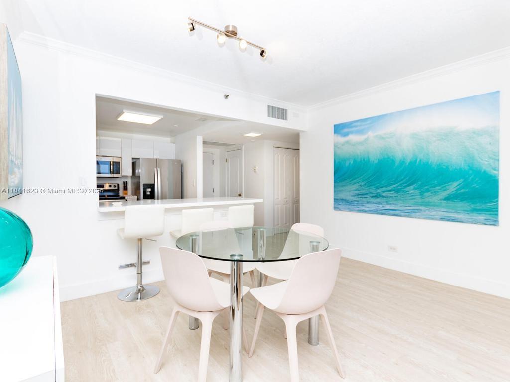 A dining area with a glass table and chairs sits adjacent to an open kitchen — 2301 Collins Ave # 625, Miami Beach FL 33139, MIAMI BEACH, FL