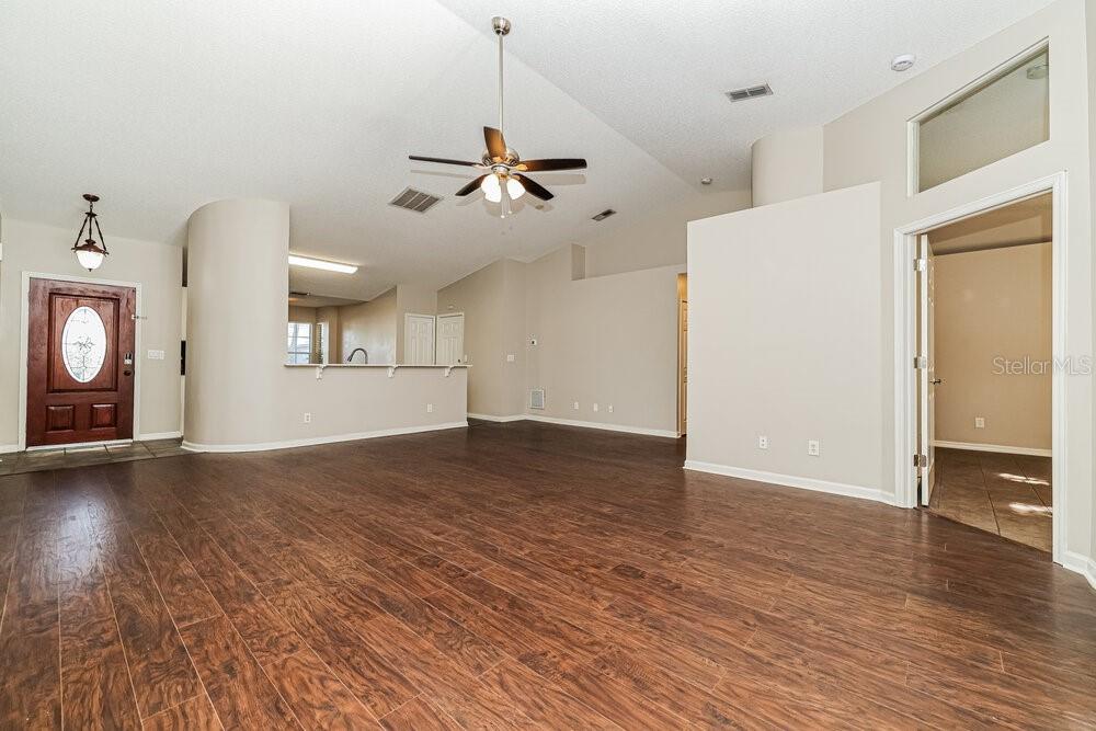 A spacious living room features dark wood-look flooring, a ceiling fan, and a front door — 4022 FONTANA PLACE, VALRICO, FL