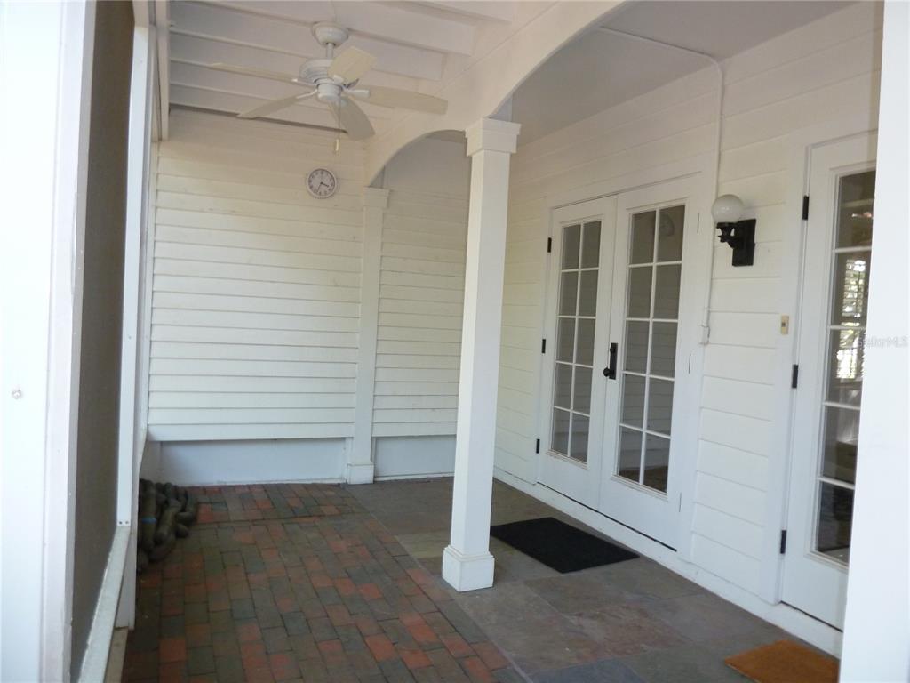 A covered porch features a brick floor, white siding, a ceiling fan, and French doors — 3302 W VILLA ROSA STREET, TAMPA, FL