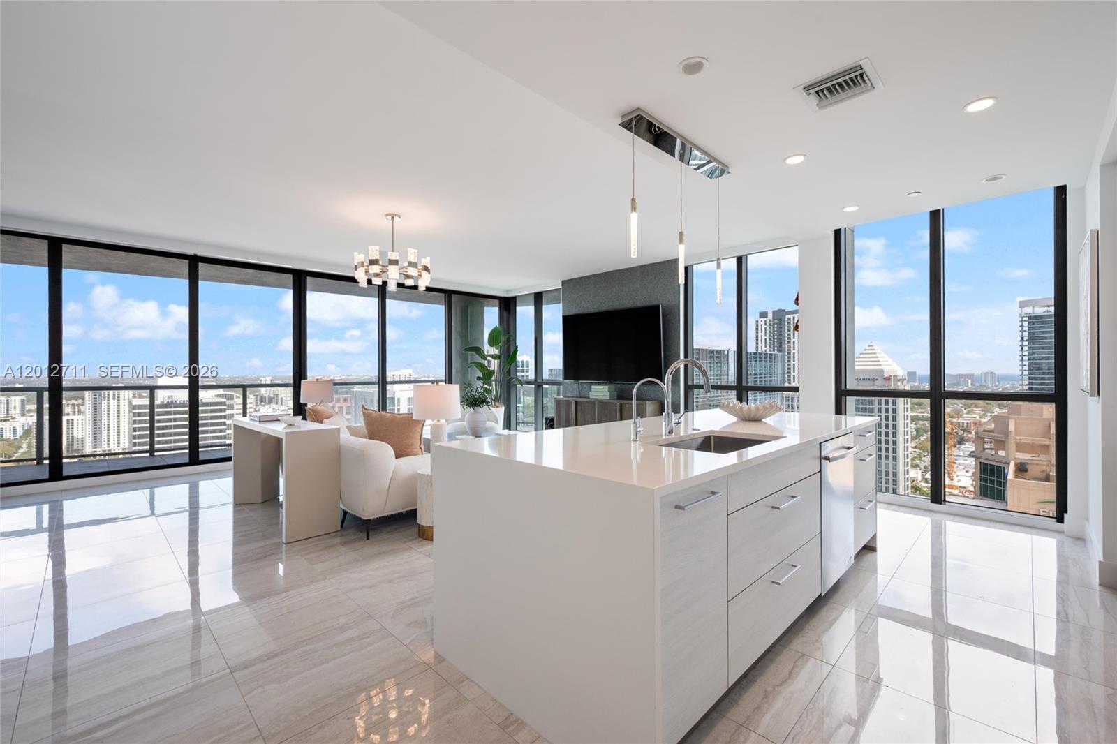 A modern kitchen island with white countertops sits in an open-concept living space with views — 100 E Las Olas Blvd # 3201, Fort Lauderdale FL 33301, FORT LAUDERDALE, FL