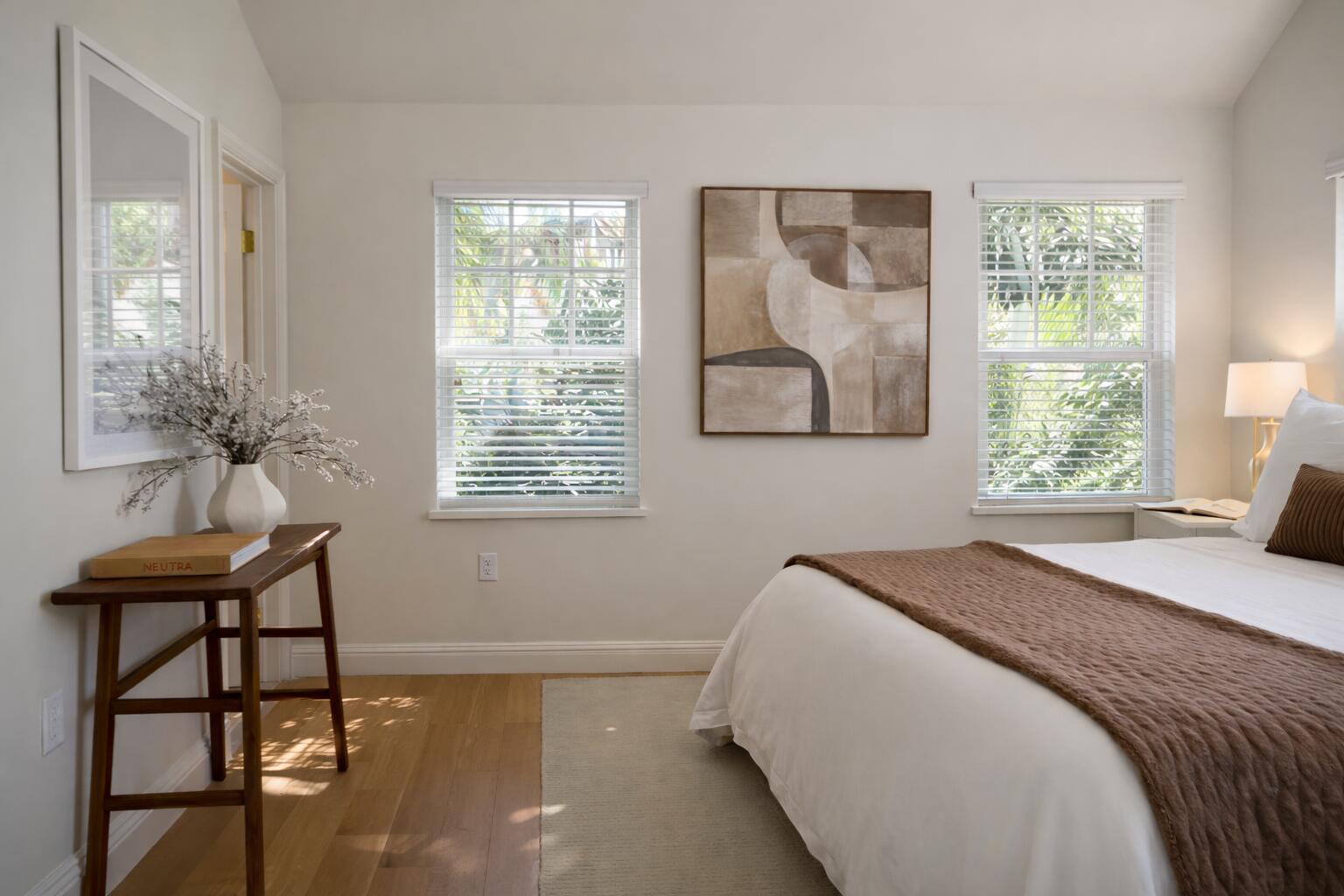 A bedroom with light wood floors, a bed, a console table, and two windows — 184 Sunset Avenue # 303, Palm Beach FL 33480, PALM BEACH, FL