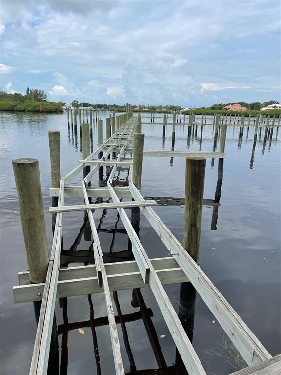An unfinished wooden boat dock structure extends over calm water with multiple pilings — 507 ANCLOTE ROAD, TARPON SPRINGS, FL