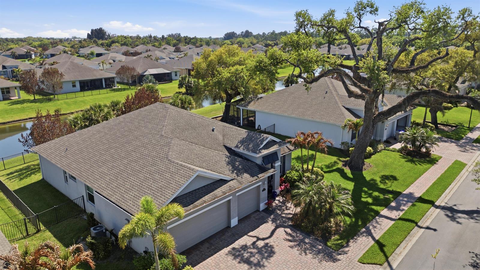 An aerial view shows two suburban houses with gray roofs, paved driveways, and a large tree — 1650 Segovia Circle, Vero Beach FL 32966, VERO BEACH, FL