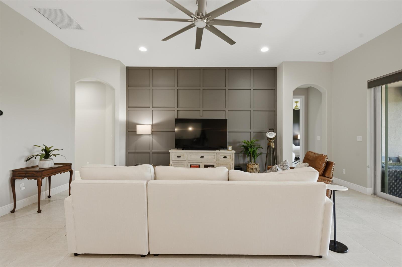 A living room features a large white sectional sofa facing a dark gray paneled accent wall — 1650 Segovia Circle, Vero Beach FL 32966, VERO BEACH, FL