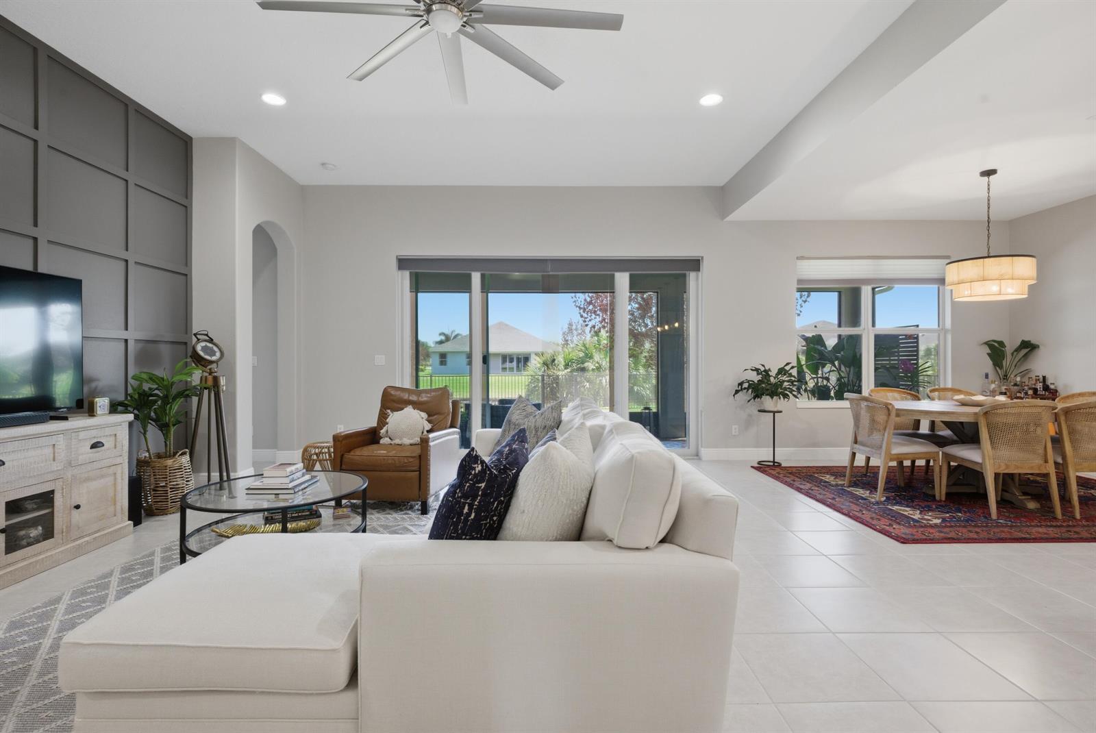 A living room with a gray accent wall, white sofa, and an adjacent dining area — 1650 Segovia Circle, Vero Beach FL 32966, VERO BEACH, FL