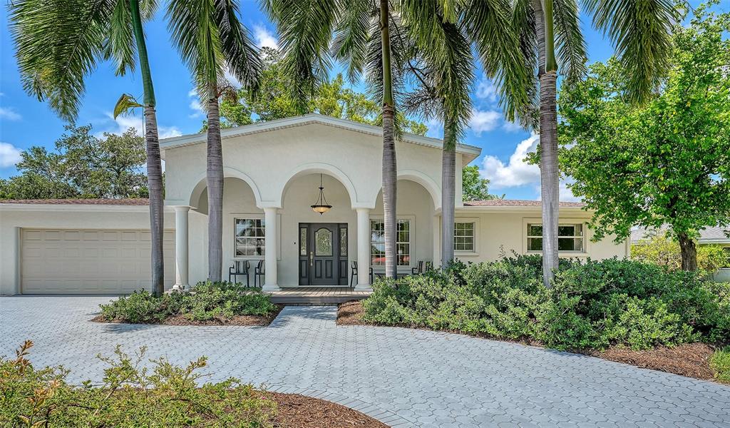 A single-story house with a paved driveway, arched entryway, and tall palm trees — 2465 FOSTER LANE, SARASOTA, FL